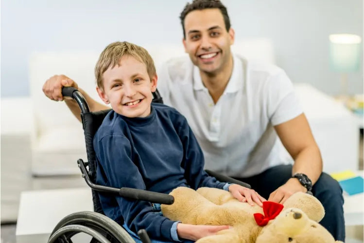 A boy with disability sitting in a wheelchair along with a health care worker.