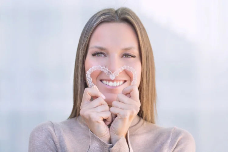 A girl holding clear aligners