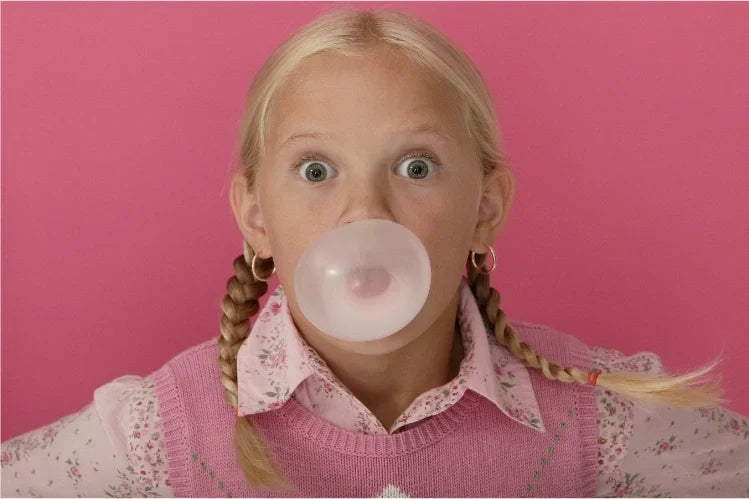 A girl blowing a bubble while chewing gum with braces