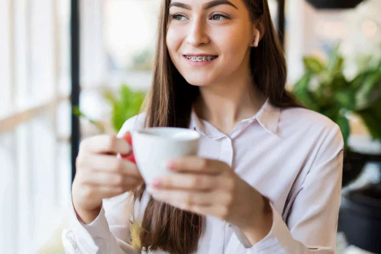 A girl having braces holding a cup of coffee