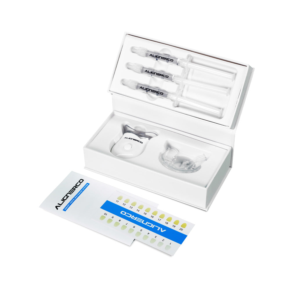 Opened Alignerco teeth whitening kit with gel syringes, mouth tray, and shade guide.