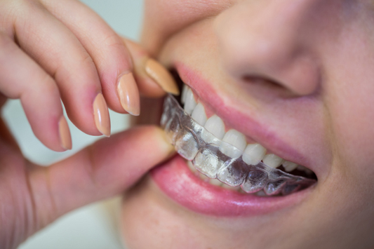 A woman smiling confidently with clear aligners