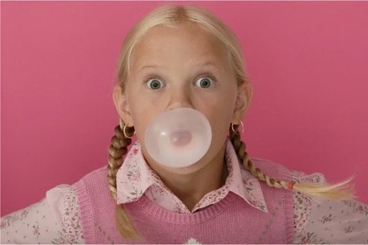 A girl blowing a bubble while chewing gum with braces