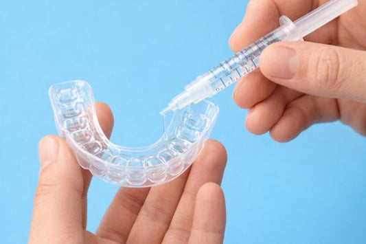 Close-up of a person gently placing a teeth whitening tray over their upper teeth.
