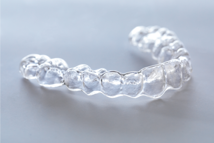 A tray of clear aligners on a grey background