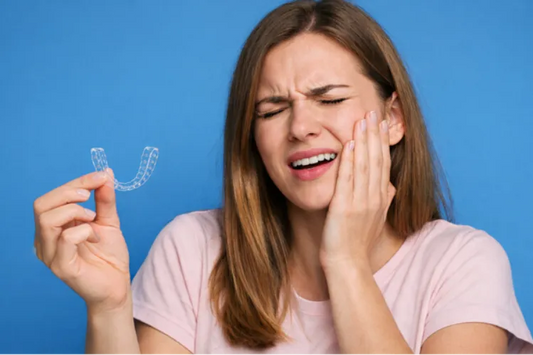  A girl holding retainers and holding her jaw in pain 