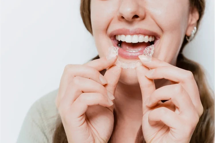 Woman holding clear aligner for teeth straightening